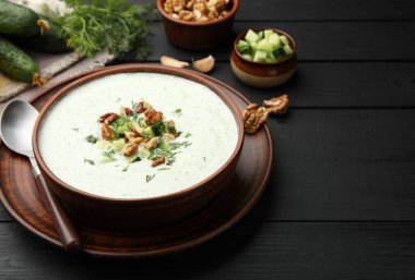 Siyah ahşap masada servis edilen dereotlu ve cevizli lezzetli salatalık çorbası.