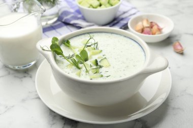 Dereotlu salatalık çorbası, mikro yeşiller ve beyaz mermer masa üzerindeki malzemeler, yakın plan.