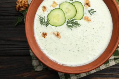 Ahşap masada dereotlu ve cevizli leziz salatalık çorbası.