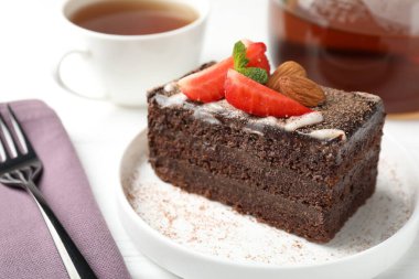 Çilekli, bademli ve beyaz masadaki çaylı lezzetli çikolatalı pasta.