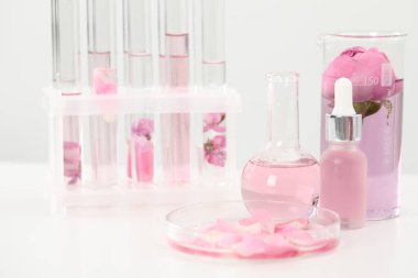 Lüks parfüm yapıyorum. Temel yağlar cam eşyalar ve çiçekler beyaz masada, yakın plan.