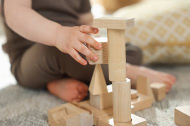 Evdeki ahşap yapı taşlarıyla oynayan sevimli küçük çocuk, yakın plan.