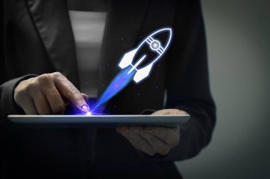 İş, başarılı bir başlangıç. Kadın karanlık arka planda tablet bilgisayar kullanıyor, yakın plan. Roket aygıttan fırlatılıyor