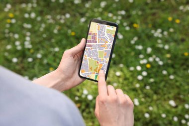 Kadın cep telefonundan şehir haritasına bakıyor, yakın plan.