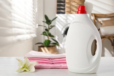 Çamaşır odasındaki masanın üzerine yumuşatıcı ve katlanmış giysiler.