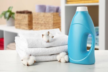 Çamaşır odasındaki masada yumuşatıcı, havlu ve pamuk çiçekleri var.