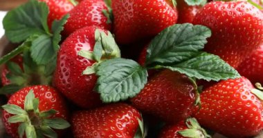 Taze olgun çilekler kasede döner masada, yakın plan