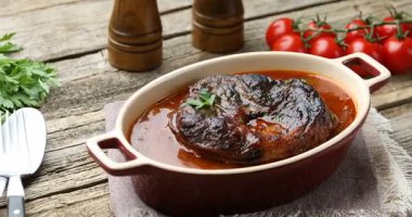 Geleneksel ossobuco yemeği biftek ile ahşap masada servis edilir, yakın plan. Kamera hareket ediyor