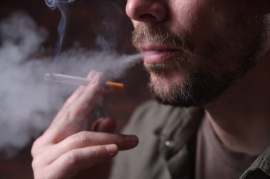 Arka planda sigara içen adam, yakın plan.