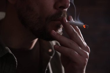 Arka planda sigara içen adam, yakın plan.