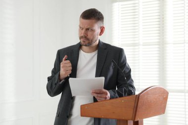 Toplum önünde konuşma korkusu. İçerideki kürsüde mikrofonlu sinirli adam.