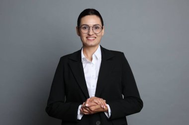 Gri arka planda kendine güvenen iş kadını