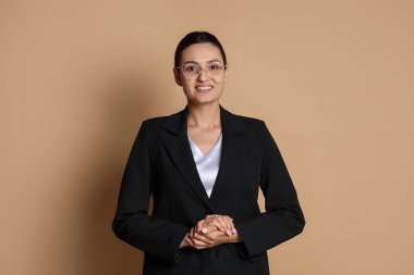 Bej arka planda takım elbiseli kendine güvenen bir iş kadını.