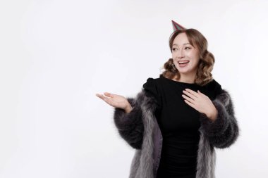 Doğum günü kutlaması. Mutlu kadın beyaz arka plandaki bir şeyi işaret ediyor. Metin için boşluk