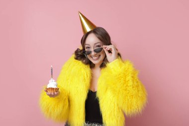 Doğum günü kutlaması. Pembe arka planda keki olan kadın.