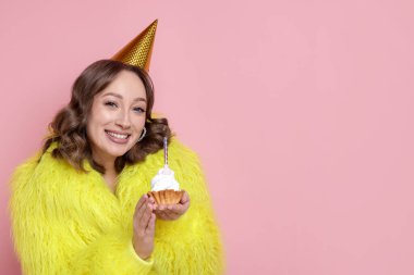 Doğum günü kutlaması. Pembe arka planda kek yiyen kadın. Metin için boşluk