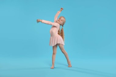 Açık mavi arka planda dans eden tatlı küçük kız.