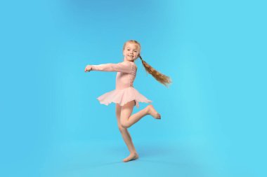 Açık mavi arka planda dans eden tatlı küçük kız.