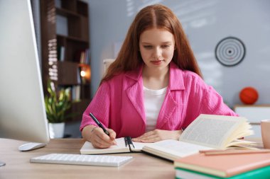 İçeride ders çalışırken not alan genç bir öğrenci.