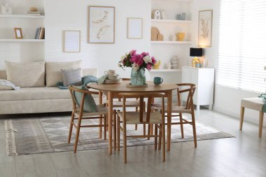 Odada güzel çiçekler ve bulaşık takımı olan yemek masası. İç tasarım