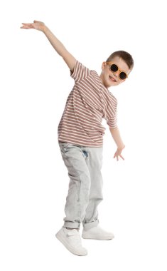 Güneş gözlüklü küçük çocuk beyaz arka planda dans ediyor.