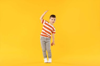 Mutlu küçük çocuk turuncu arka planda dans ediyor