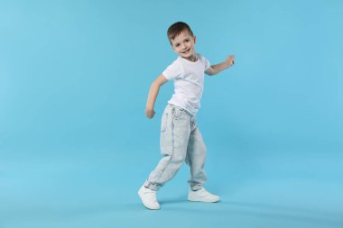 Açık mavi arka planda dans eden mutlu küçük çocuk. Metin için boşluk