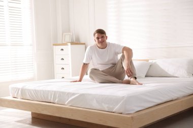 Genç adam evde yumuşak bir döşekle yatakta yatıyor.