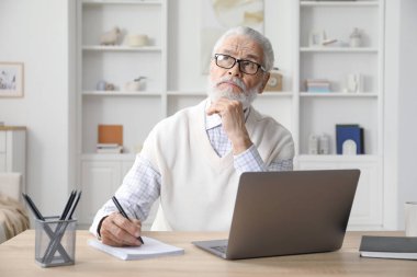 Üst düzey adam içeride masa başında öğrenirken not alıyor. Kendi kendine çalışma.