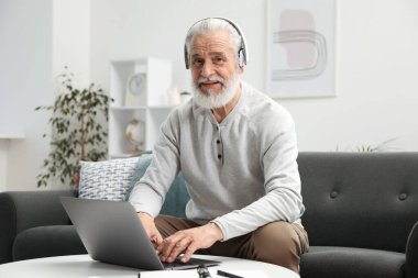 Üst düzey bir adam internette bilgisayarla kapalı bir masada öğreniyor. Kendi kendine çalışma.