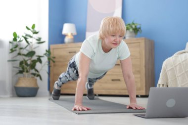 Spor giyim bölümünde son sınıf öğrencisi. Evde online ders sırasında kalas egzersizi yapıyor.