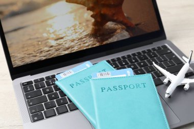 Pasaportlar, uçuş biletleri, uçak modeli ve dizüstü bilgisayar masada, yakın plan.