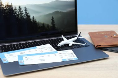 Pasaportlar, uçuş biletleri, uçak modeli ve laptop ahşap masada, yakın plan.