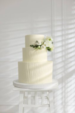 İçerideki masada çiçeklerle süslenmiş nefis düğün pastası.