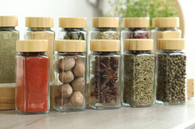 Kapalı alanda, ahşap masadaki kavanozlardaki farklı aromatik baharatlar.