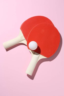 Ping pong raketleri ve pembe zemin üzerinde top, düz yatıyordu.