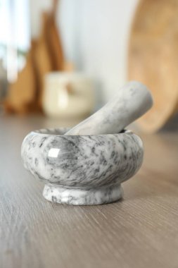 Mutfaktaki ahşap masada mermer harç ve tokmak, yakın plan.