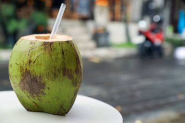 Yeşil hindistan cevizi, ferahlatıcı bir içecek ve açık havada beyaz masada saman, yakın plan. Metin için boşluk