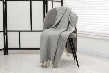 Gri yün battaniyeli rahat bir koltuk.