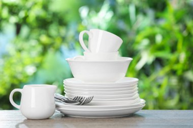 Ahşap masada, bulanık yeşil arka planda farklı temiz tabaklar.