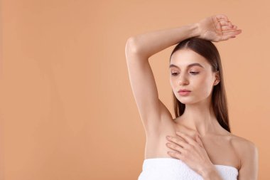 Bej arkaplandaki epilasyondan sonra pürüzsüz cilt gösteren genç kadın, metin için boşluk