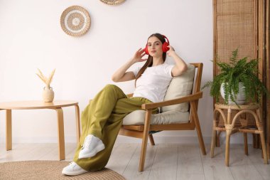 Kulaklıklı güzel bir kadın evdeki rahat koltukta dinleniyor.