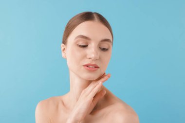 Açık mavi arka planda büyüleyici genç bir kadının portresi.