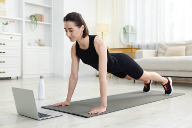 İnternetteki derste koçla tahta egzersizi yapan bir kadın. Spor ve sağlıklı yaşam tarzı