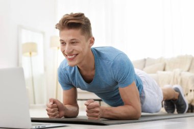 Evdeki koçla çevrimiçi derste tahta egzersizi yapan adam. Spor ve sağlıklı yaşam tarzı