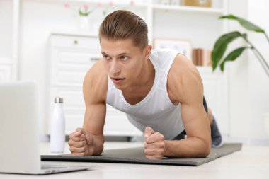 Evdeki koçla çevrimiçi derste tahta egzersizi yapan adam. Spor ve sağlıklı yaşam tarzı