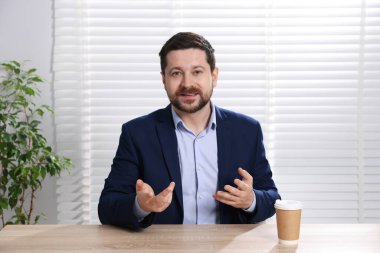 Gülümseyen çevrimiçi hoparlör. İçerideki masada web kamerasından görüntüsü olan webinar.