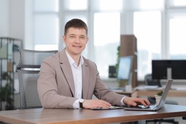 Ofiste masada dizüstü bilgisayarda çalışan adam