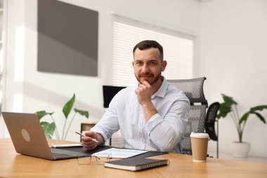 Ofiste masa başında çalışan yakışıklı adam.