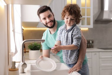Baba ve oğlu evde birlikte bulaşık yıkıyorlar.